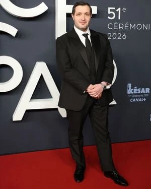 Karim Leklou wearing a Berluti black shawl collar tuxedo on the red carpet.