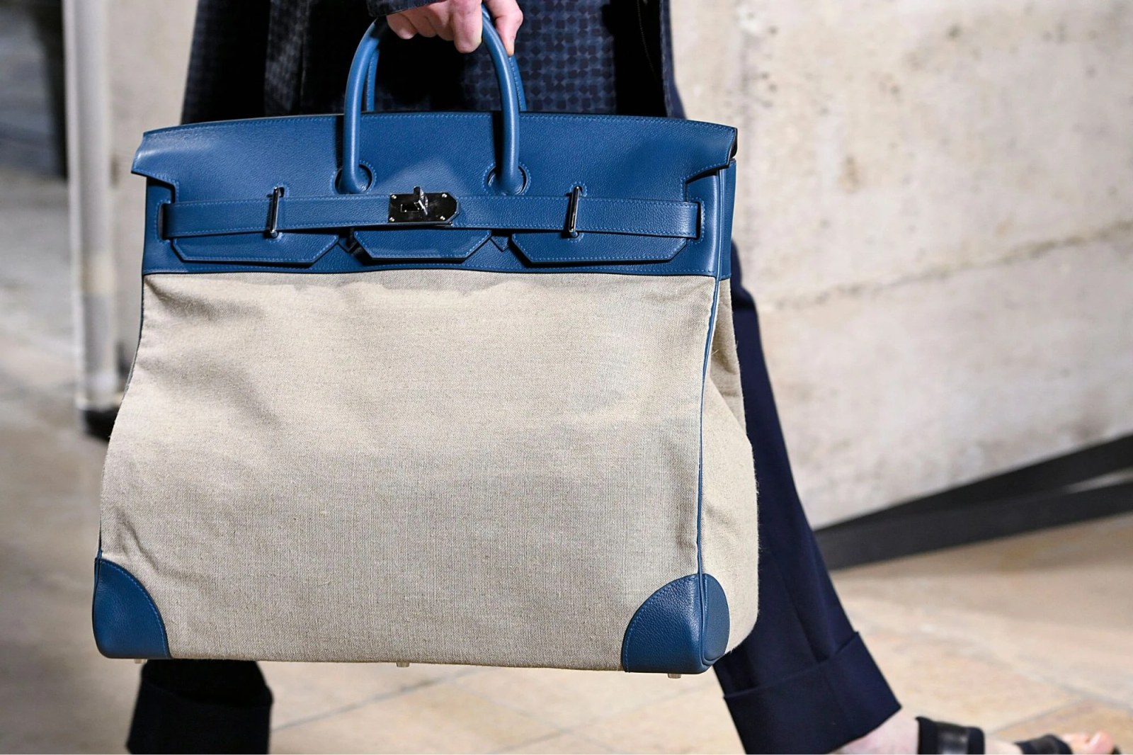 A man carrying a luxury Hermès travel bag.