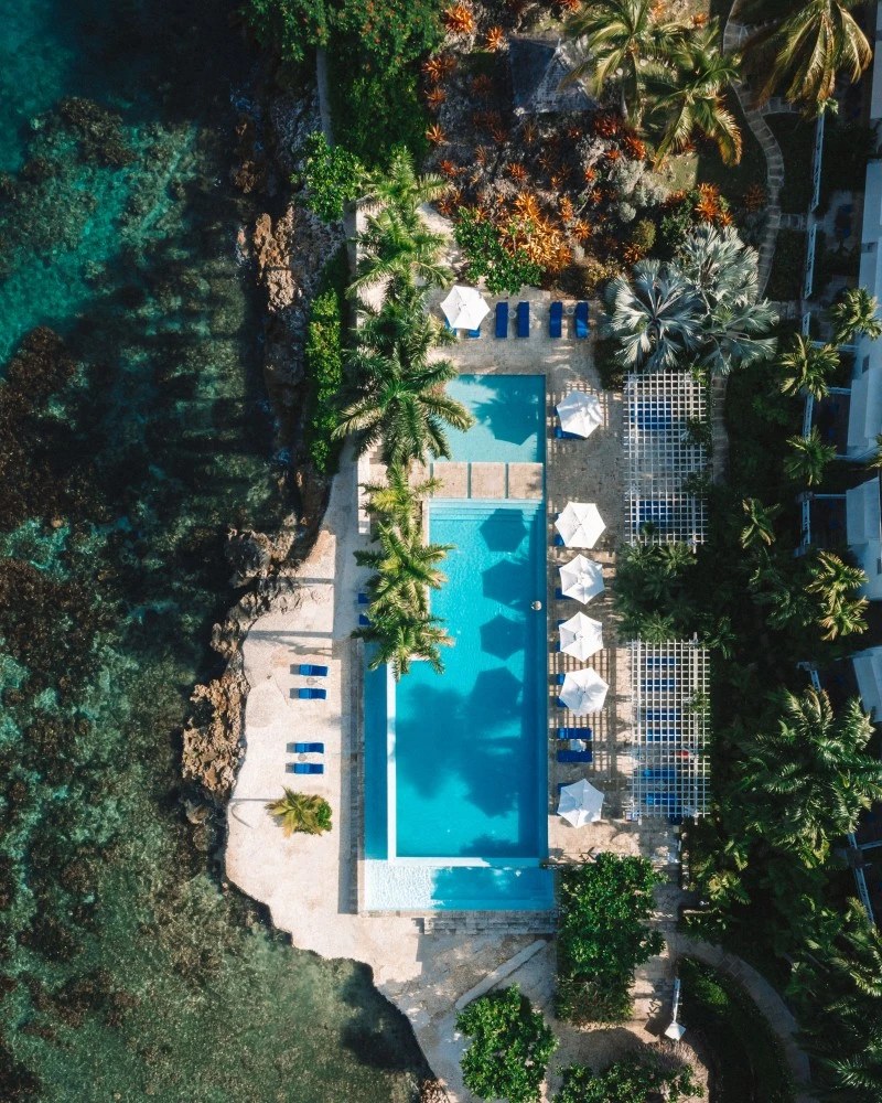 the mahogany and white-on-white palette; in the ceiling fans that actually cool the air. Everything is understated, chosen to disappear into the pleasure of being there. <img decoding=